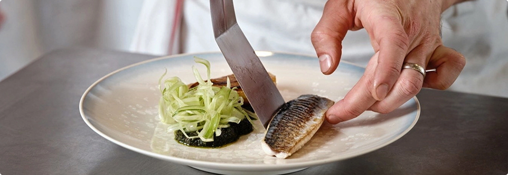 A cook prepares a plate of fish
